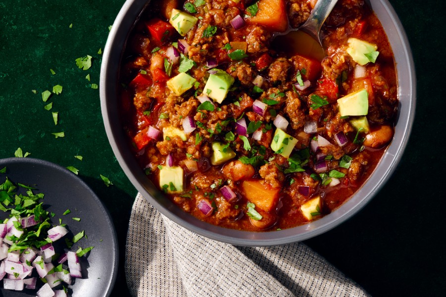 Bowl of vegetarian chili made with MorningStar Farms Crumbles and garnishes on the side